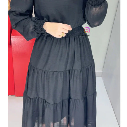 Vestido negro con tejido texturizado y detalles de encaje guipur en el cuello.